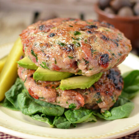 Moist grilled prosciutto, olive, and sun-dried tomato turkey patties on a plate.